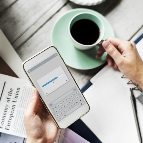 Hands Holding Downloading Mobile Phone with Coffee Cup Beverage